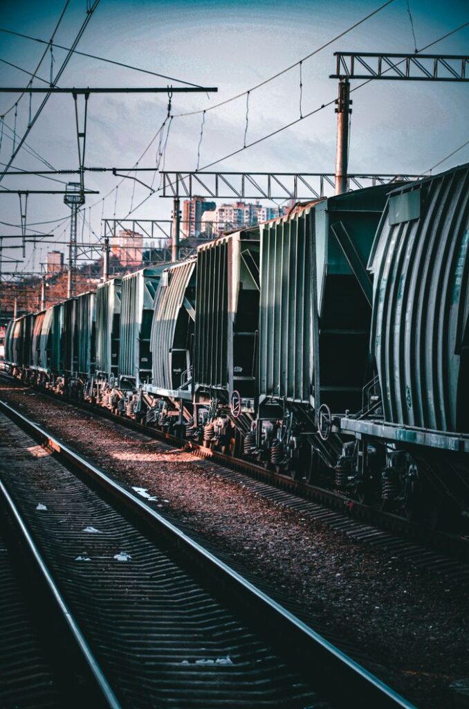 pexels-photo-15630611-15630611 Long freight train on railway tracks in an urban area with overhead cables.